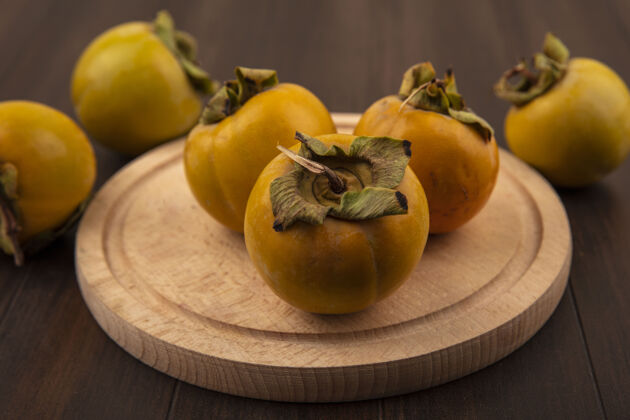 顶部新鲜的有机柿子水果在木制厨房板上的木桌上俯瞰柿子水果新鲜