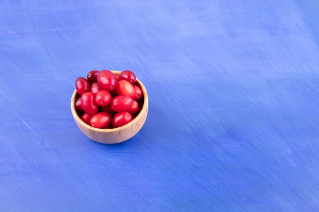 水果蓝色表面上装满玫瑰果的小木碗有机营养美味