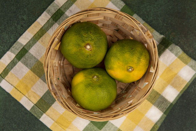 视野俯瞰黄绿色格子毛巾上篮子里的橘子新鲜橘子篮子