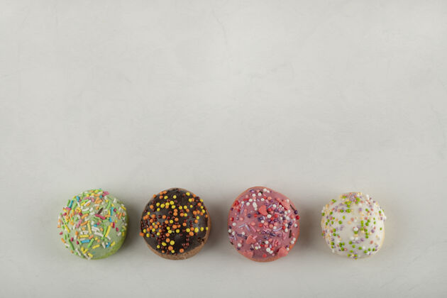 许多白色表面上五颜六色的甜甜甜圈巧克力不同圆形