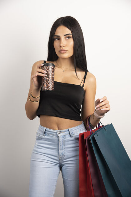 年轻人黑发女人摆着购物袋和咖啡高质量的照片购买包休闲