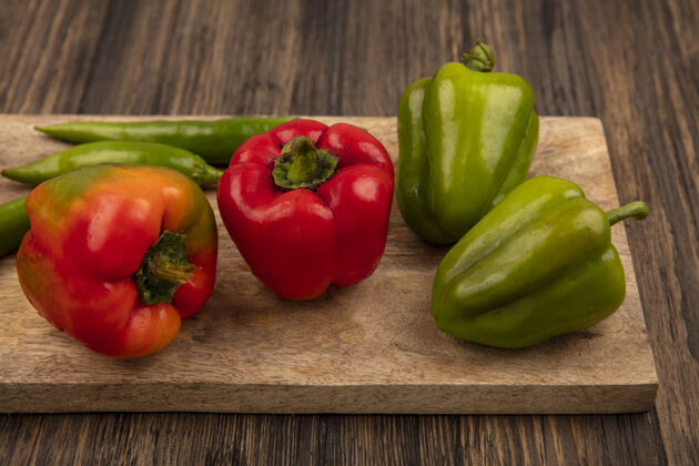 木材红色和绿色甜椒的顶视图在木制背景上的木制厨房板上胡椒食物烹饪