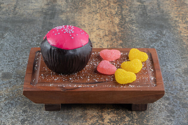 糖果巧克力饼干和粉红色釉面和糖果在木板上糕点美味盘子