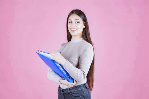 积极女孩拿着一个蓝色的项目文件夹 看起来很成功和快乐人清单女性