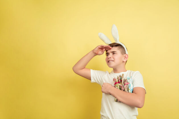 情感期待装饰白人男孩作为复活节兔子在黄色背景上复活节快乐的问候美丽的男模人类情感的概念 面部表情 节日复制空间人脸潮流自信