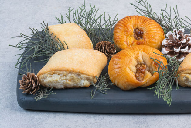 松枝不同的曲奇 松果和松枝放在木托盘上 放在大理石上喜悦甜点饼干