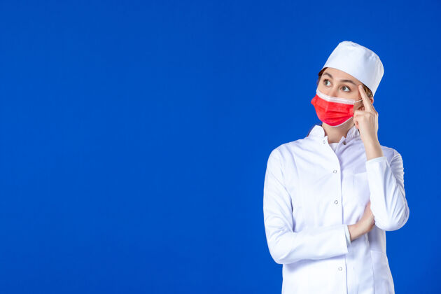 药品正面图蓝色墙上戴着红色防护面具的年轻护士 穿着医疗服病毒医疗疾病