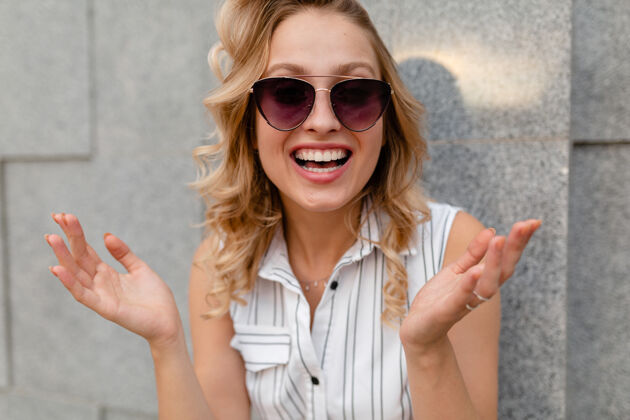眼镜年轻迷人的时尚女性微笑的肖像穿着夏日时尚的连衣裙戴着墨镜走在城市街道上坦诚的微笑街头配件太阳镜