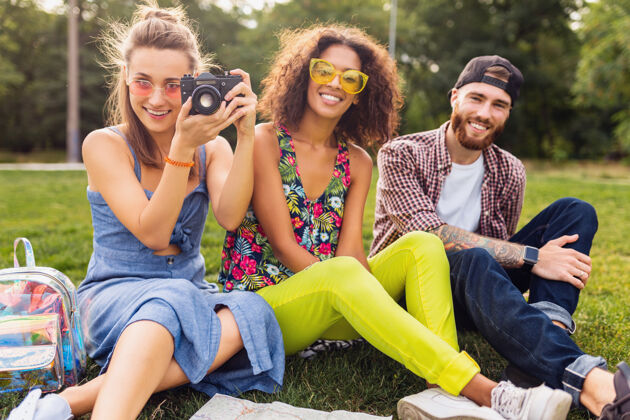 酷快乐的年轻朋友们一起坐在公园里 男女一起玩 旅游 拍照 聊天 微笑旅行女孩青春