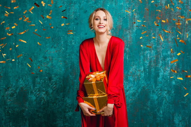 优雅迷人的快乐微笑的女人穿着时尚的红色连衣裙 用礼物庆祝圣诞节和新年美丽女性礼物