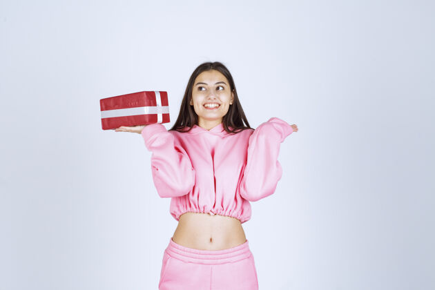 服装穿着粉色睡衣的女孩手里拿着一个红色长方形礼盒 看上去很满意女性人类人类