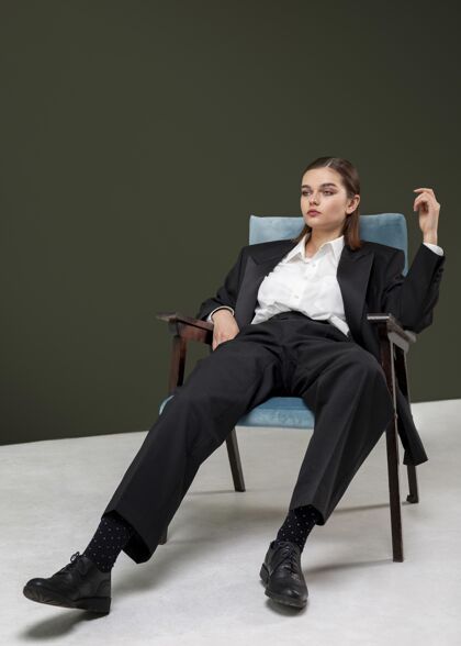 女权主义优雅的女模特穿着夹克套装坐在扶手椅上全新的女性概念服装时尚模特