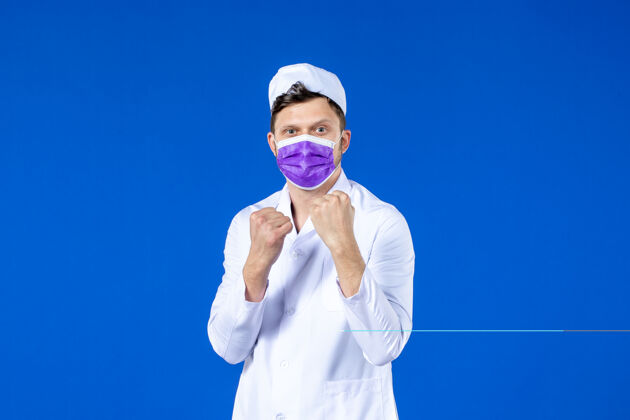 男医生身穿医疗服的男医生和蓝色斗士站的紫色面罩的正视图护士大流行疾病