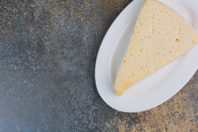 美味把一片黄奶酪放在白盘子里早餐有机奶制品