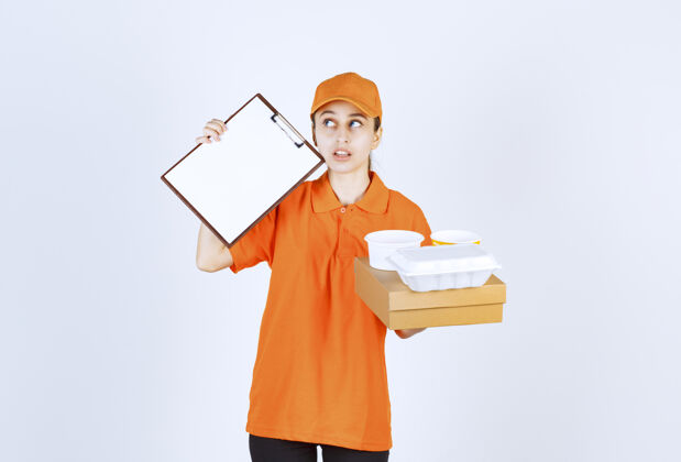 货物身着橙色制服的女快递员手拿一个纸板箱和一个塑料外卖箱 要求签名休闲购物工人