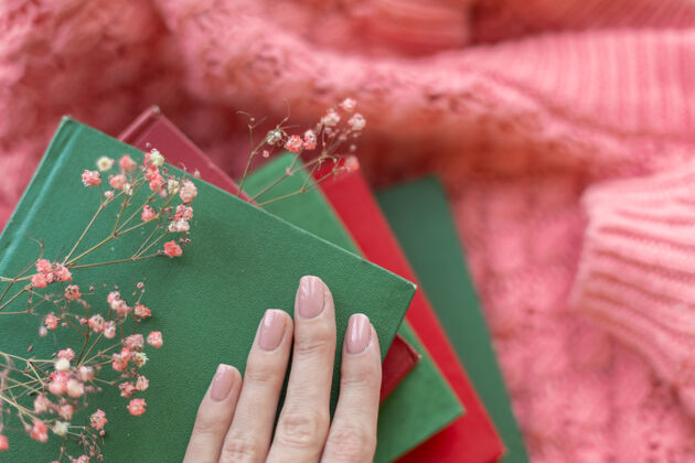 休闲一堆红绿相间的书 粉色温暖的针织毛衣上挂着干花开花春天的心情爱好