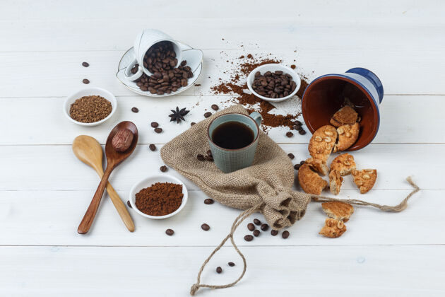 粗麻布一套咖啡豆 磨碎的咖啡 曲奇饼 木制勺子和咖啡在一个木杯和袋子的背景高角度视图咖啡馆木头