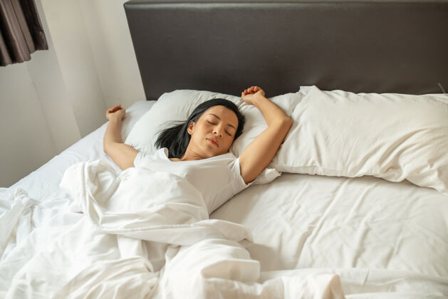 小睡安静的年轻女士穿着睡衣躺在床上睡着了休息躺下积极
