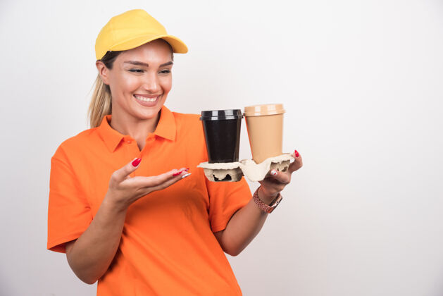 送货金发女信使指着白墙上的两杯咖啡快递订单塑料杯