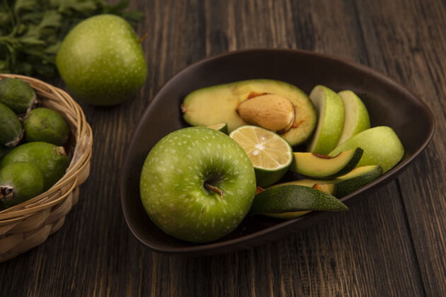 苹果有机水果切片的俯视图 例如苹果 鳄梨 碗上的酸橙和木制表面桶上的酸橙水果人饭