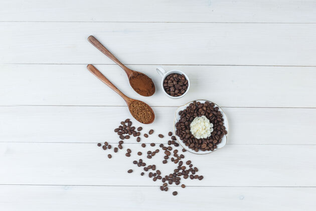 浓缩咖啡咖啡豆在杯子和盘子里与磨碎的咖啡 木制背景上的花朵俯视图谷物香气自然
