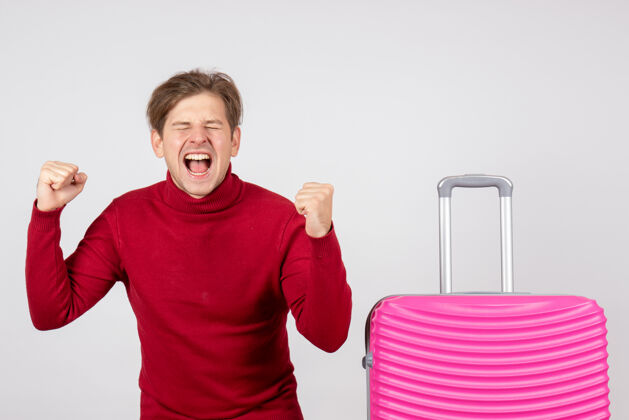 微笑正面是年轻的男性 带着粉红色的包 在白色的墙上欢欣鼓舞假期旅行情感