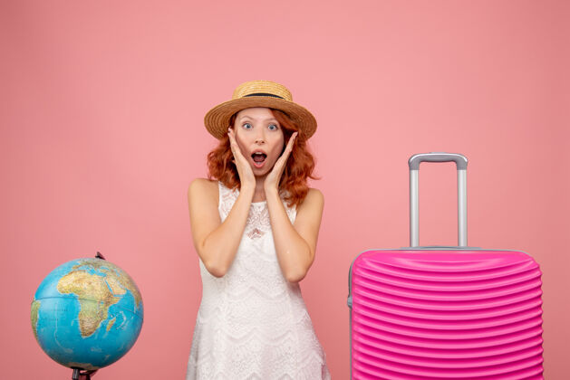 模型年轻女性游客的正面图 粉红色的墙上挂着粉红色的包旅行包头发