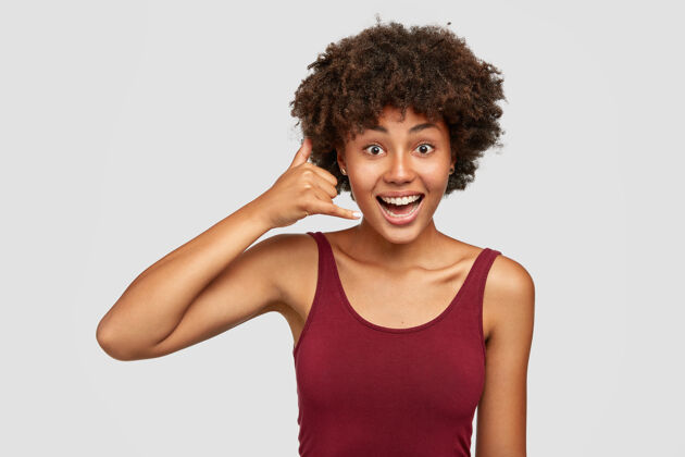 朋友高兴的黑人妇女 非洲式发型 使电话手势与手一样 通过手机通话背心个人姿势
