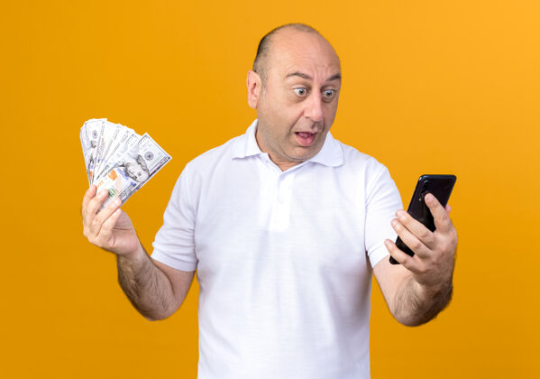惊喜一个不经意的成熟男人拿着现金 看着隔离在黄色墙上的电话休闲现金电话