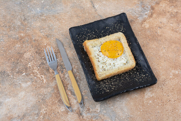 切片黑盘子上的带香料的鸡蛋吐司和餐具美味面包面包房