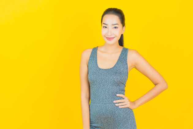 训练在黄色的墙上 描绘一位穿着运动服准备锻炼的美丽亚洲年轻女子运动肖像皮肤护理