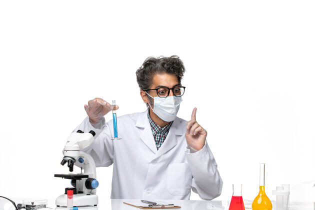 溶液正面图中年科学家穿着特制的衣服坐着拿着装有溶液的烧瓶实验室坐着拿着