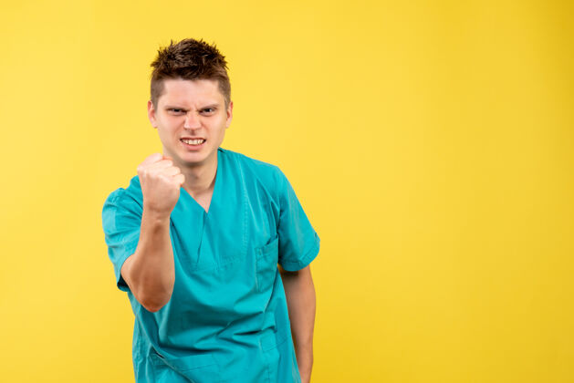 年轻男性医生正面图黄色背景上穿着医疗服的年轻男医生医学医学人
