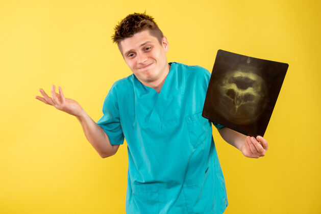 健康正面图身穿医疗服的年轻男医生拿着黄色背景的x光片X光男人医院