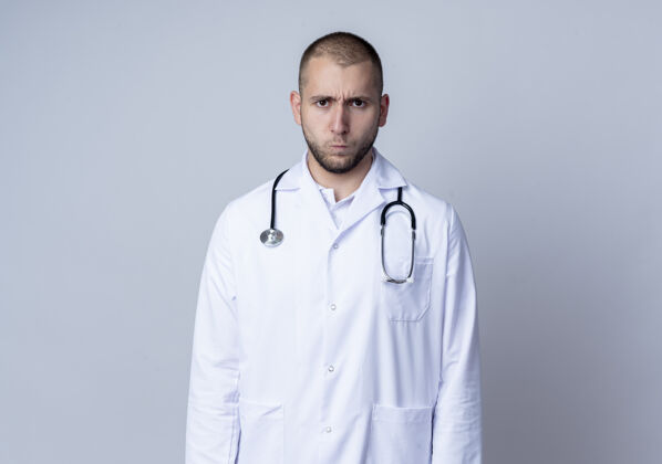 穿皱眉的年轻男医生 穿着医用长袍 脖子上戴着听诊器 站在白色的空间里 看上去与世隔绝医疗太空周围