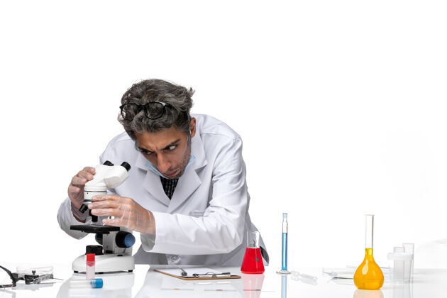 工作正面图身着白色医疗套装的中年科学家固定显微镜化学工作人