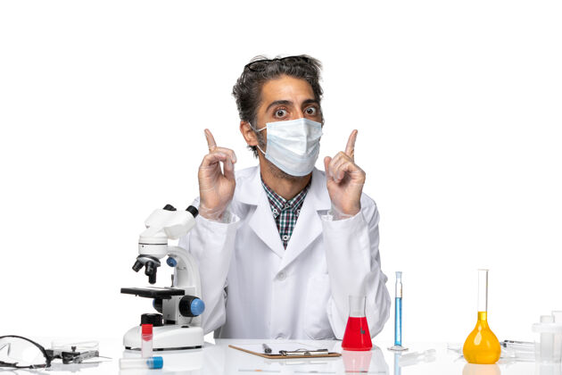 解决方案前视图穿着白色医疗服的中年科学家围坐在桌子旁 拿着解决方案化学实验室外套