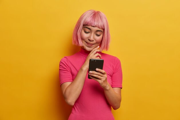 粉色假发迷人的年轻女子 时尚的发型 微笑着看着智能手机华丽请高兴
