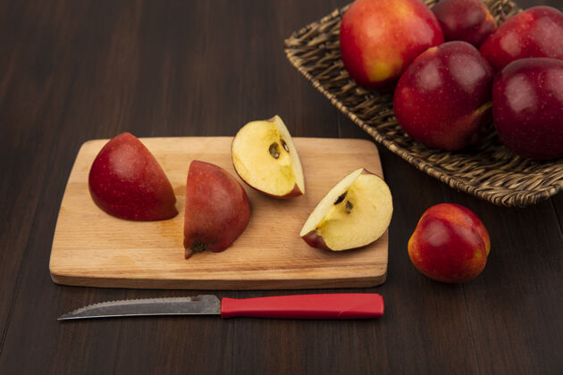 特写柳条托盘上的甜红苹果俯视图 木制厨房板上有苹果片 木制墙上有小刀托盘视图农业