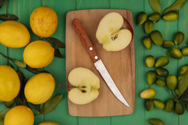 顶部木制厨房板上的甜苹果俯视图 刀子上绿色的金盏花和黄色的柠檬被隔离在绿色的木墙上木材视图食品