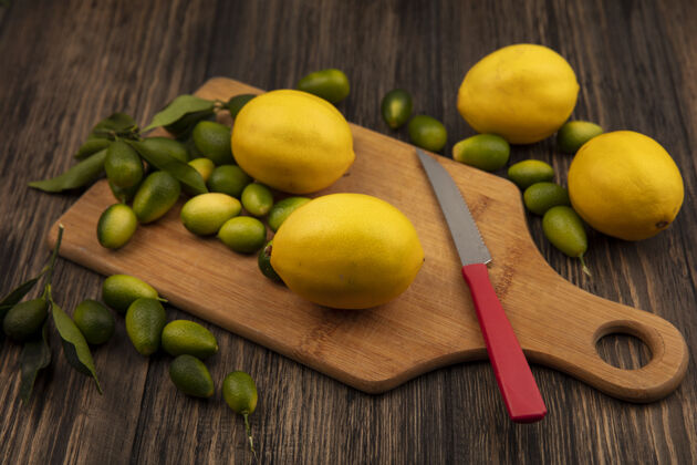 饮食木制厨房板上的彩色水果（如柠檬和金盏花）俯视图 木制墙壁上有小刀厨房人农业