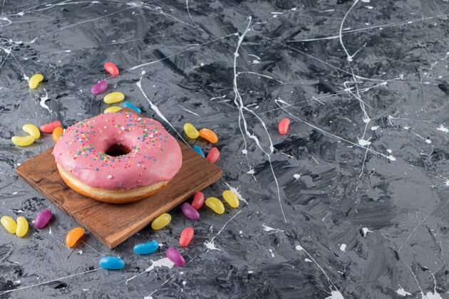 糖色彩斑斓的糖果旁边的一块木板上 放着上釉的甜甜圈 放在混合桌上卡路里饼干烘焙