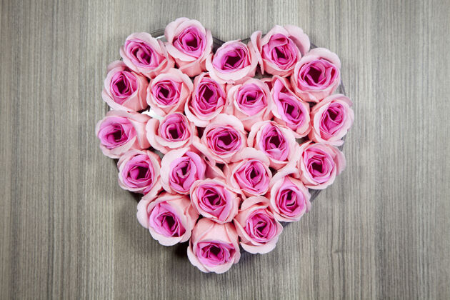 叶高角度特写镜头粉红色玫瑰在一个木制表面的心形束礼物开花