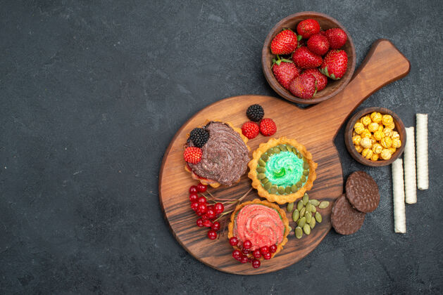 美味俯瞰美味的奶油蛋糕和水果在黑暗的桌子甜饼干饼干饼干多汁甜点