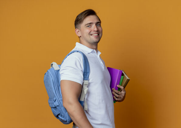 抱着笑容可掬的年轻帅气男生背着书包拿着书孤零零地放在橘子上穿年轻男
