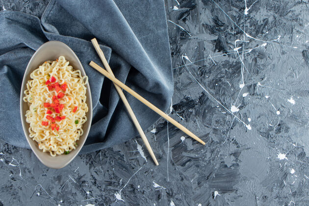 午餐一碗面条放在筷子旁边的一块布上 放在大理石的背景上布料面食美味
