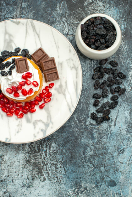 水果顶视图美味的奶油蛋糕与巧克力石榴和葡萄干浅黑色的背景饼干糖石榴