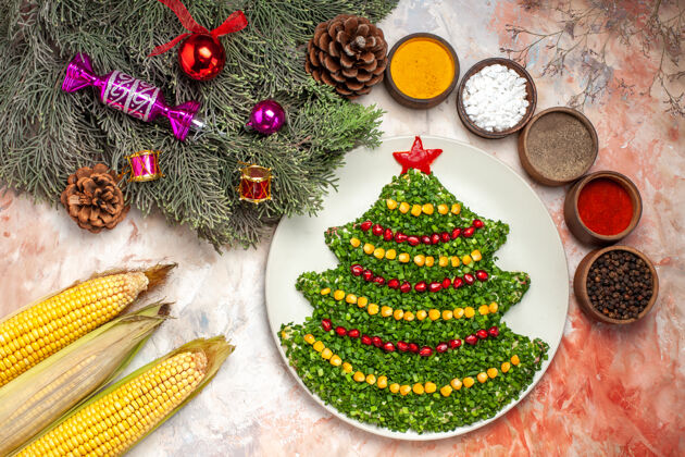 新的顶视图美味的绿色沙拉在新年树形状与调味品在轻背景圣诞节背景冬天