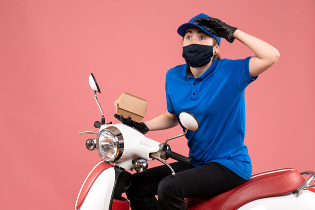 自行车正面是戴着面具的女快递员 粉红色的小食品包装传送带摩托车工作