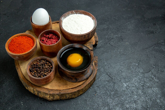 面团前视图：灰色空间上有面粉和鸡蛋的不同调味品正面食物面粉